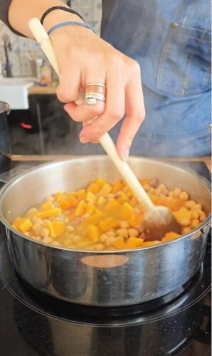 Cuisinier mélangeant un ragoût de citrouille et pois chiches.