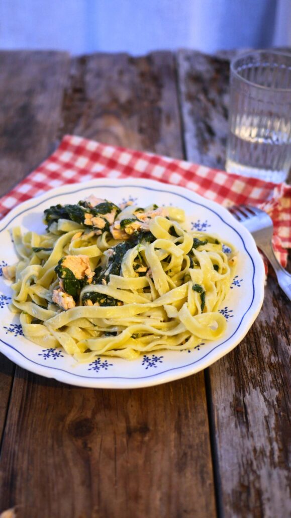 Assiette de tagliatelles avec des morceaux de saumon frais et des épinards cuits