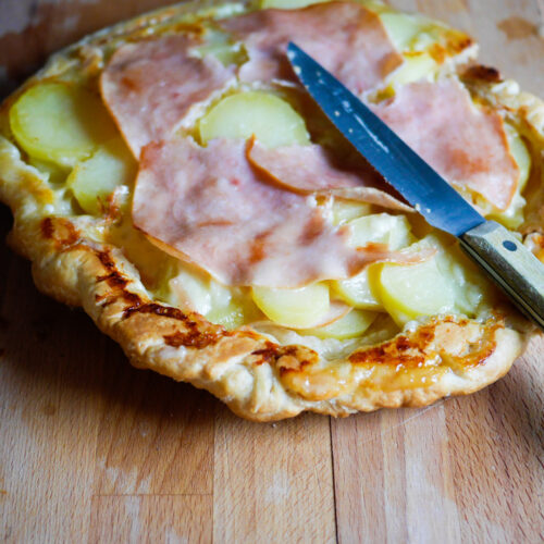 Tarte aux pommes de terre et jambon sur bois.