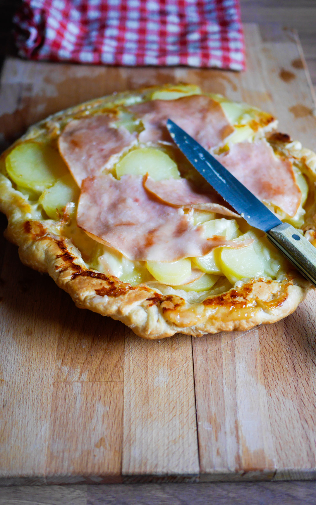 Tarte aux pommes de terre et jambon sur bois.