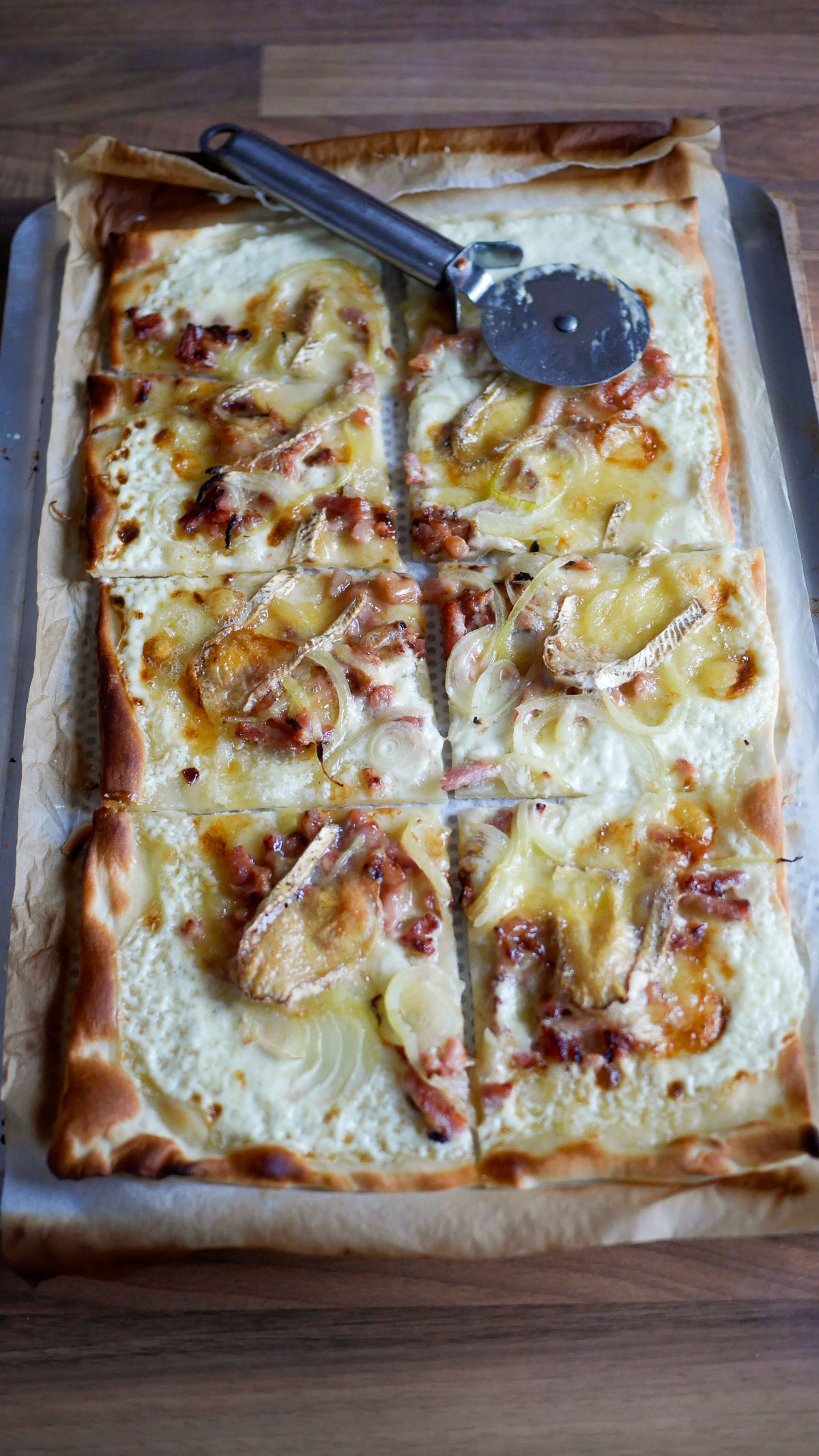 Flammekueche coupée avec trancheuse à pizza, sur plaque