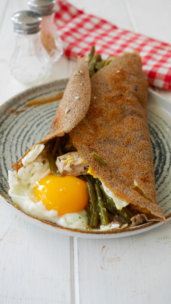 assiette avec une galette de sarrasin garnie de haricots verts, poulet, oeuf et cheddar