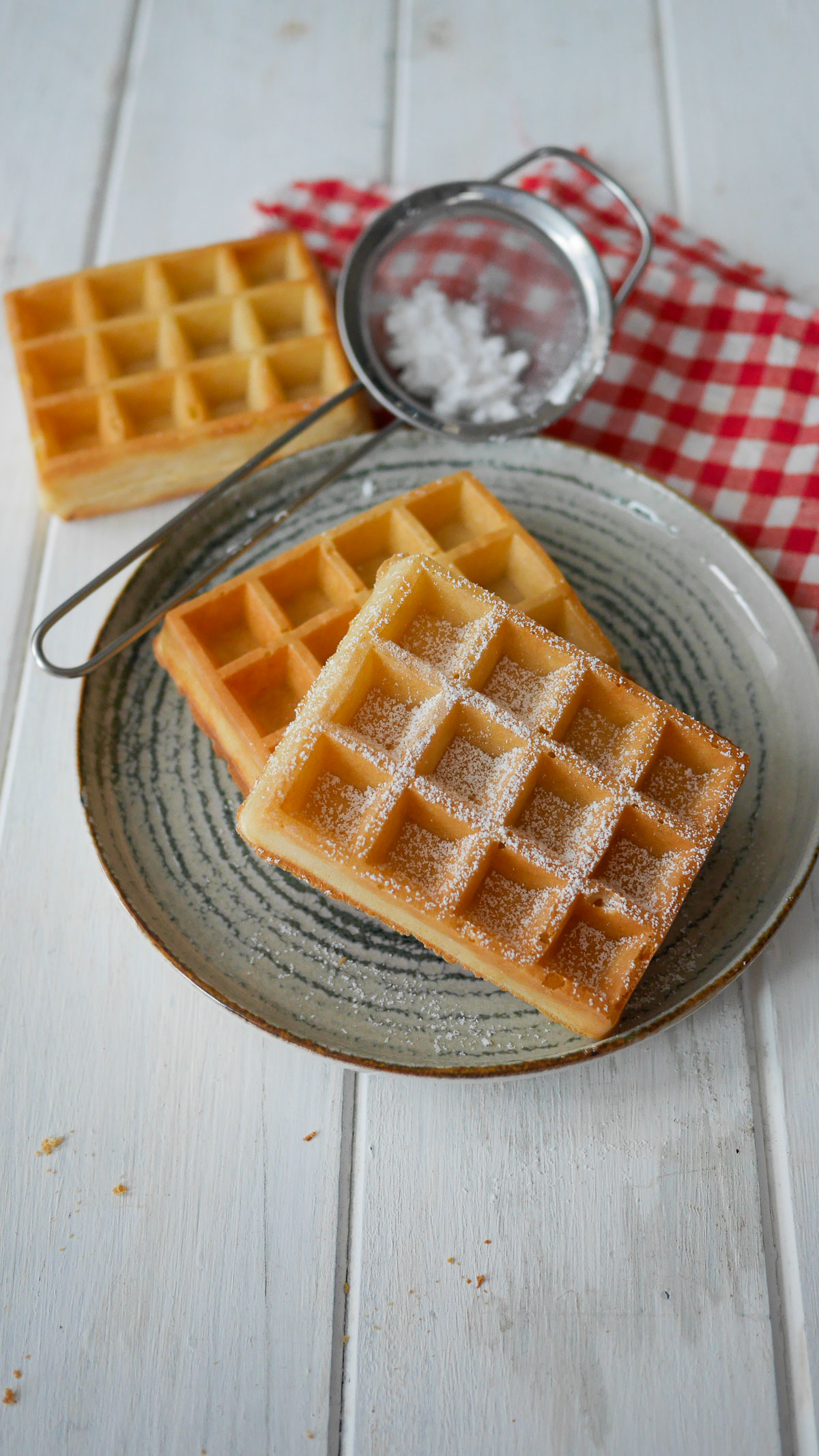 Gaufres belges saupoudrées de sucre glace sur une assiette.