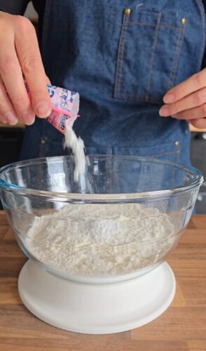 Préparation de pâte : levure versée dans un bol de farine.
