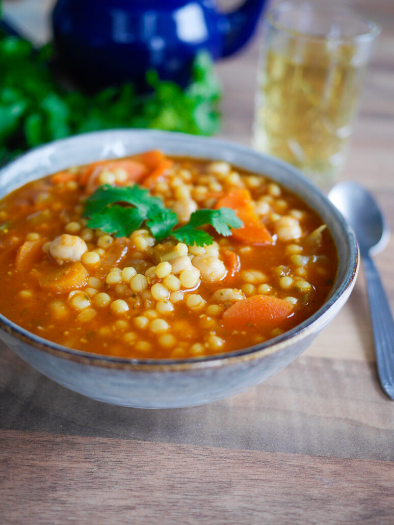 Bol de soupe berkoukes avec des pâtes plombs, des pois chices, un bouillon à la tomate, des carottes et de la coriandre