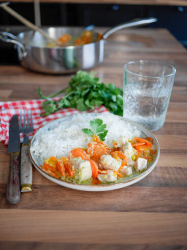 Plat de riz, poulet et carottes sur table en bois.