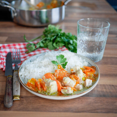Plat de riz, poulet et carottes sur table en bois.