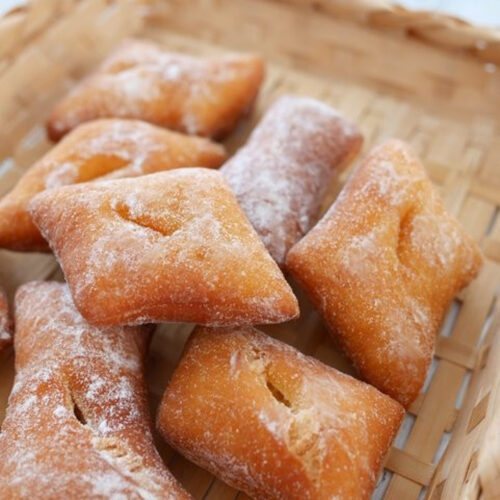 Bugnes lyonnaises saupoudrées de sucre glace dans un panier