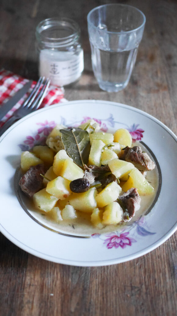 Assiette de ragout agneau et pommes de terre, avec un verre d'eau et une serviette de table