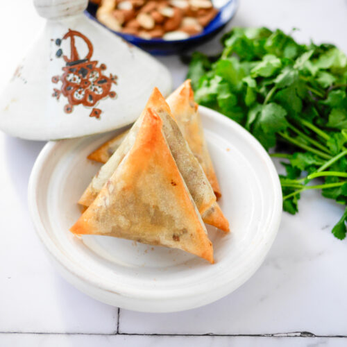 Briouats marocains, tajine et coriandre sur table blanche