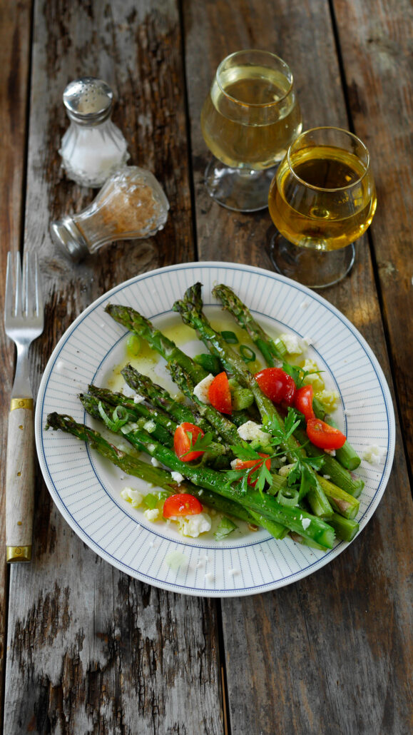 Assiette d'asperges vertes, grillées au barbecue, servie avec de l'oignon nouveau, de la feta et des tomates cerises