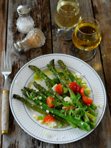 Assiette d'asperges, tomates, féta, vin blanc sur bois.