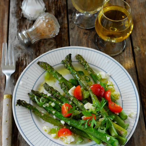 Assiette d'asperges, tomates, féta, vin blanc sur bois.
