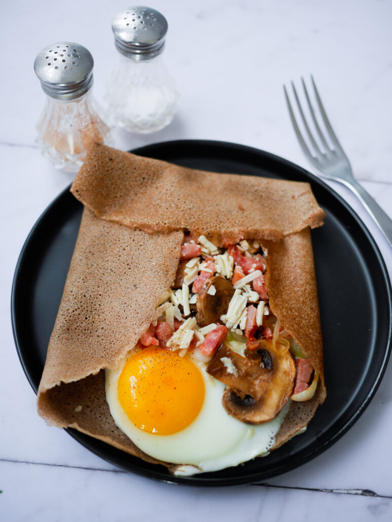galette de blé noir garnie d'oeuf coulant, de champignons de paris et de lardons