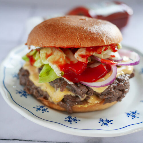 Hamburger appétissant avec fromage, salade et oignon rouge.