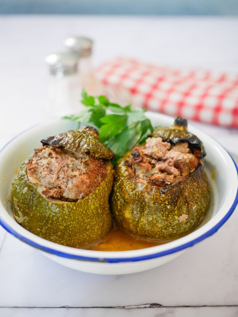 2 courgettes farcies posées dans une assiette sur une table avec une serviette à carreaux