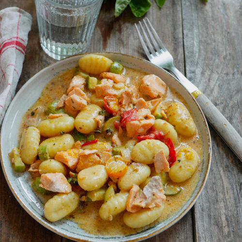 Gnocchis au saumon, courgette et tomates sur table bois