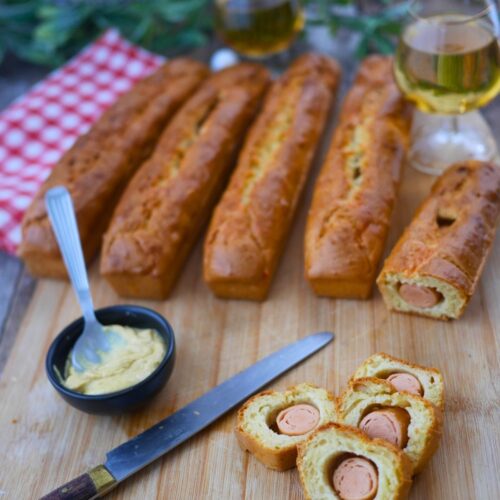 Pains saucisses, moutarde et vin blanc sur planche à découper.