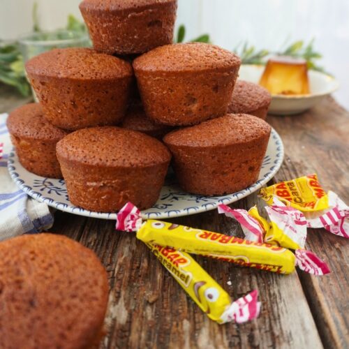 Pile de muffins et bonbons Carambar sur table bois.