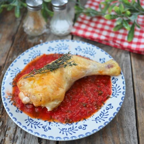 Assiette avec une cuisse de poulet à la sauce tomate