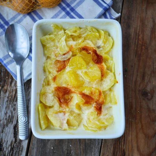 plat de gratin dauphinois sur une table avec torchon et pommes de terre