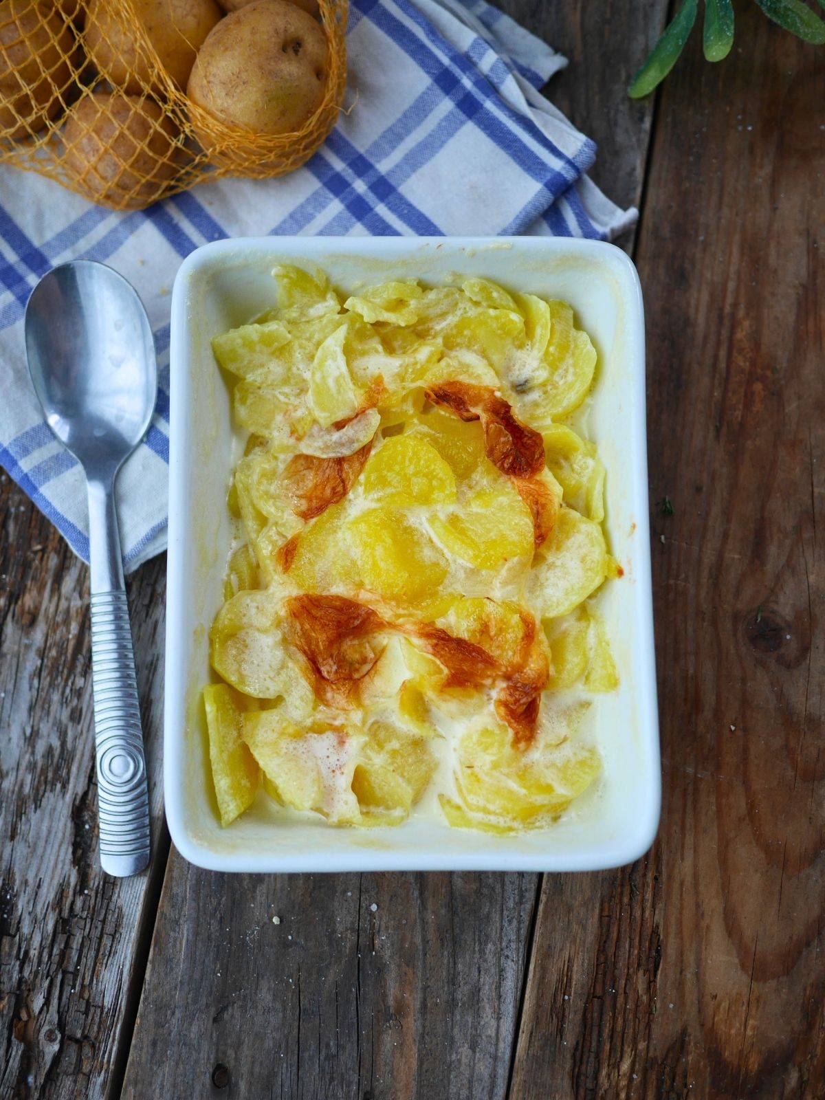 plat de gratin dauphinois sur une table avec torchon et pommes de terre