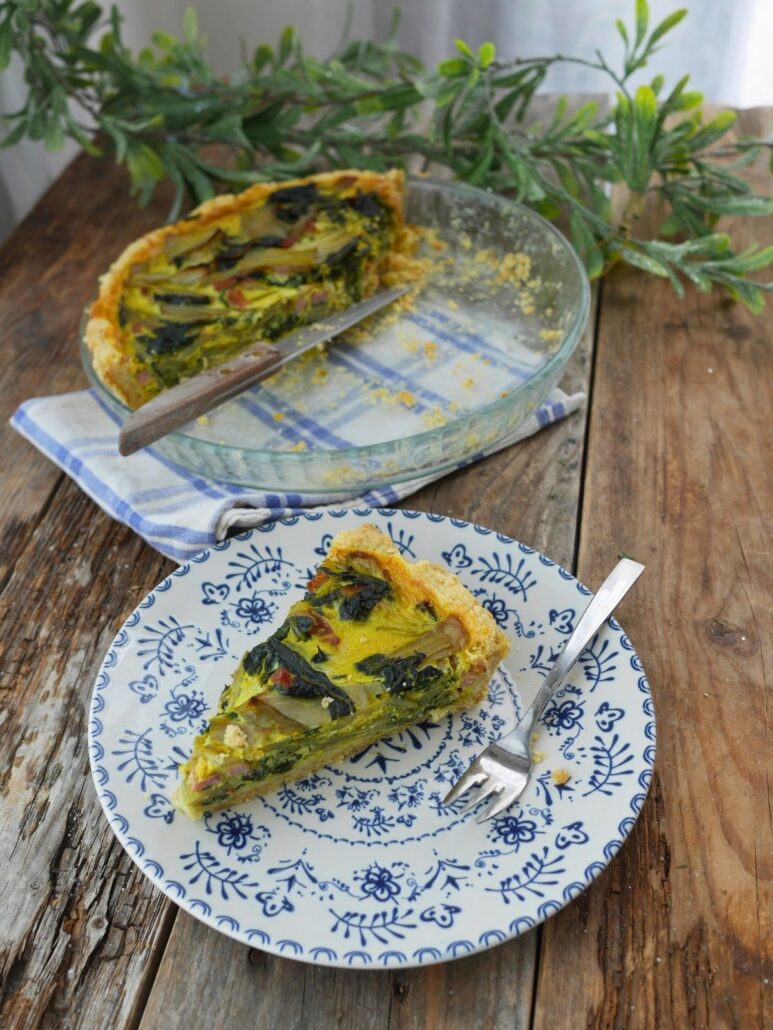 quiche aux blettes et lardons coupée en part, servie dans une assiette