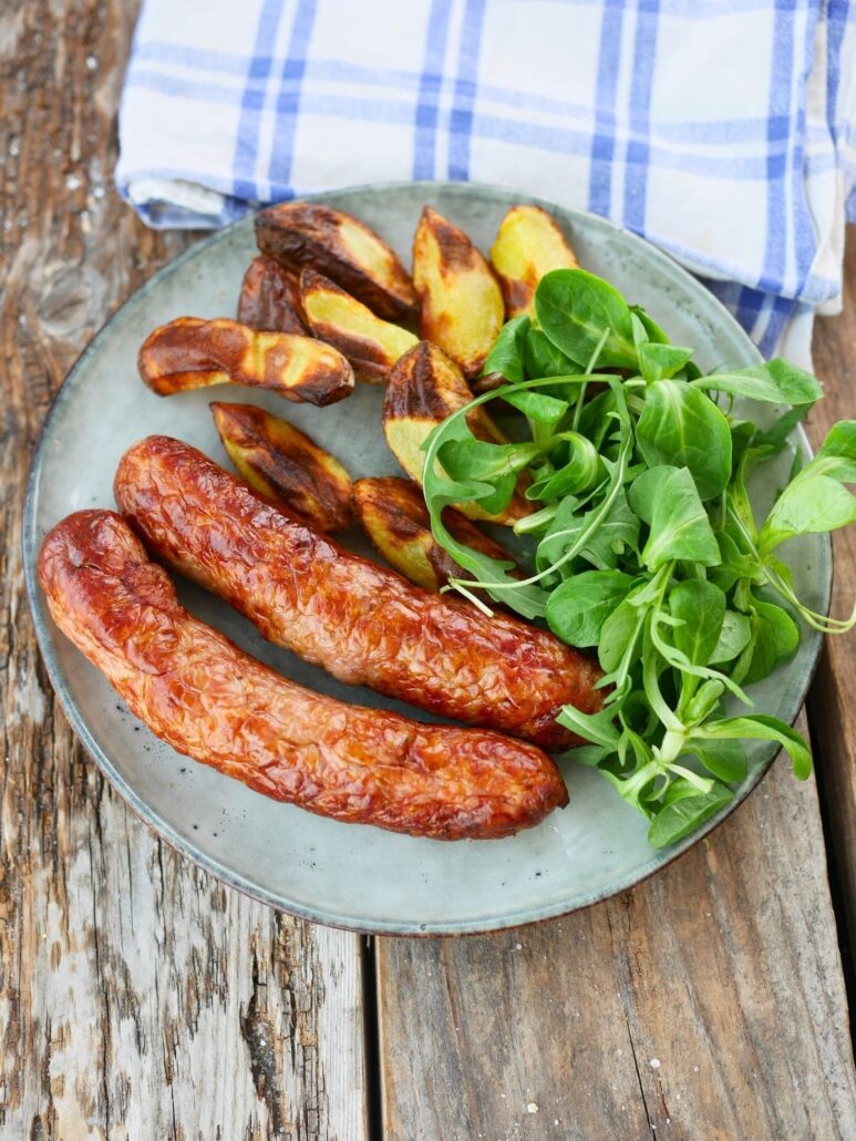 Assiette de saucisses cuites à l'airfryer avec potatoes et salade