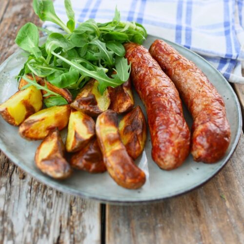 assiette de saucisses cuites à l'airfryer avec des potatoes et salade verte