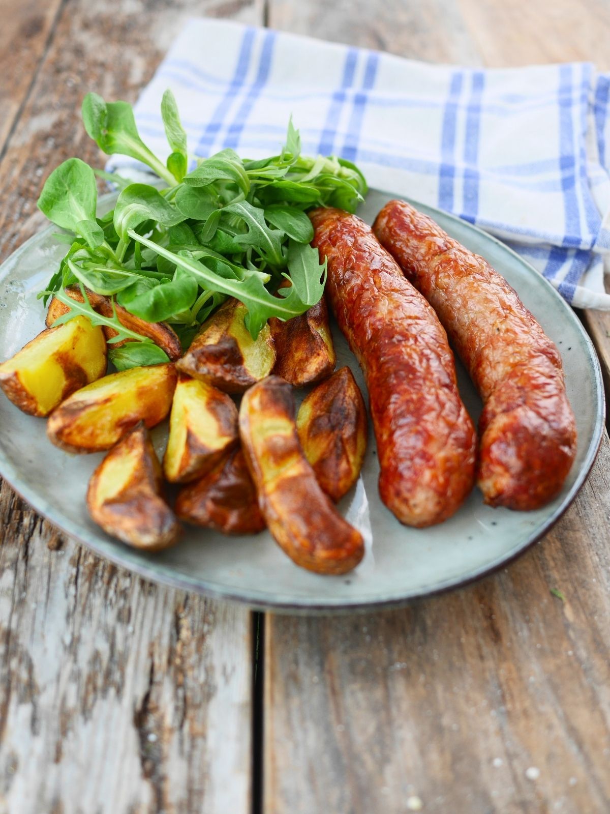 assiette de saucisses cuites à l'airfryer avec des potatoes et salade verte