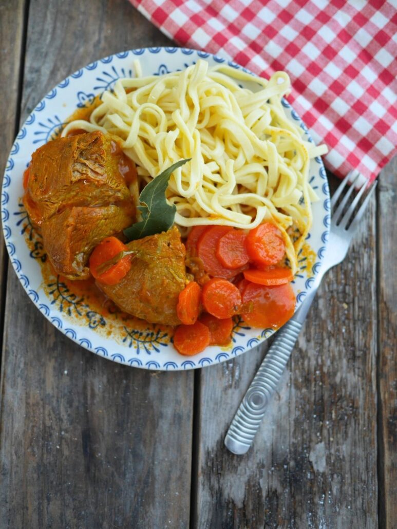Sauté de veau aux carottes dans une assiette sur une table en bois